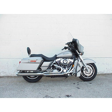 Gray motorcycle parked on a concrete surface with a white wall background