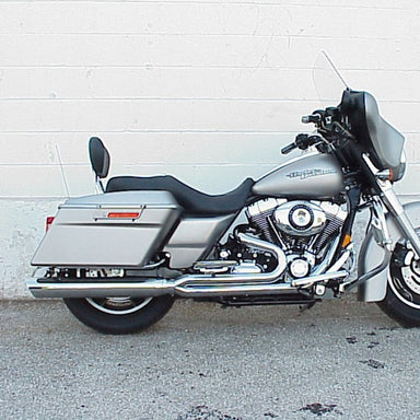 Silver motorcycle parked on a concrete surface with a light gray wall in the background