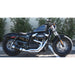 Black motorcycle parked on a street with a white wall and greenery in the background