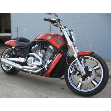 Red and black motorcycle parked in front of a gray brick wall.
