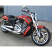Red motorcycle parked on a concrete surface with a gray wall in the background