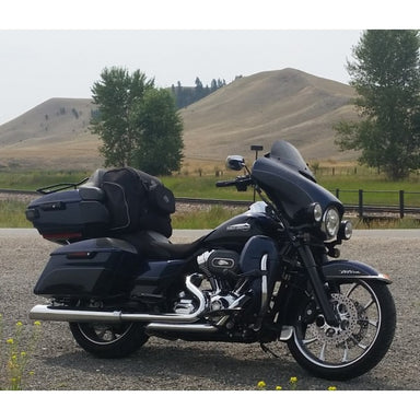 Black motorcycle with luggage on a gravel road with a scenic background