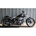 Black motorcycle parked on a concrete surface with a metal wall background