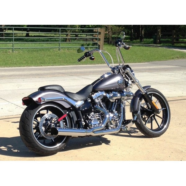 Motorcycle parked on a paved road with grass and trees in the background