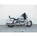 Gray motorcycle parked on a concrete surface with a white wall background