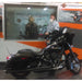 Black motorcycle in a showroom with a man and a large mirror reflecting the interior.
