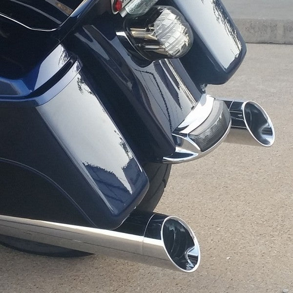 Close-up of a motorcycle with chrome exhaust pipes on a concrete surface.