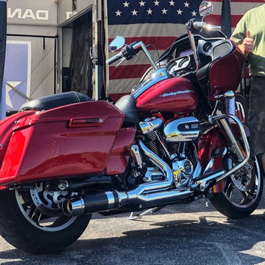 Red motorcycle with chrome details parked in front of a building with an American flag.