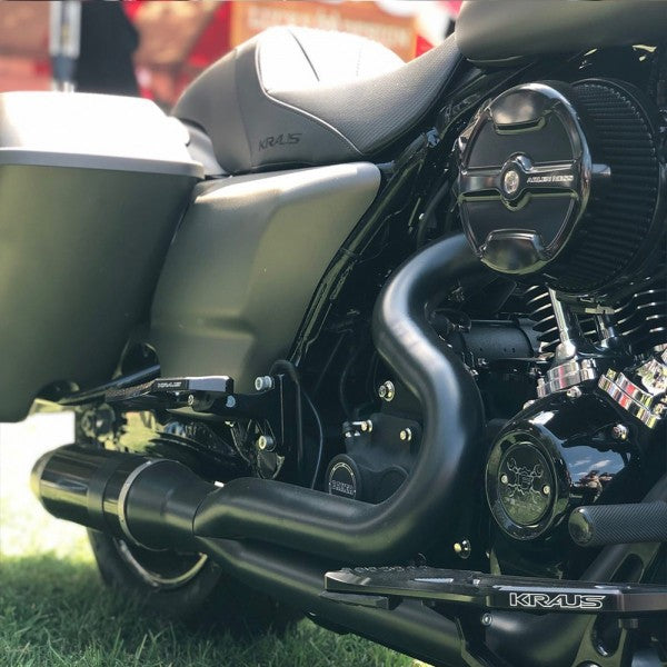 Close-up of a motorcycle with 'KRAUS' branding on a grassy background
