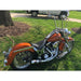 Orange motorcycle parked on grass with a tree and white vehicle in the background
