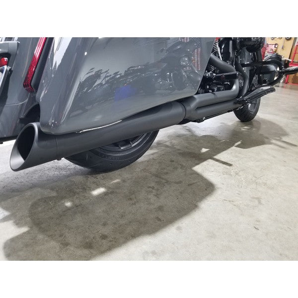 Close-up of a motorcycle exhaust system on a concrete floor.
