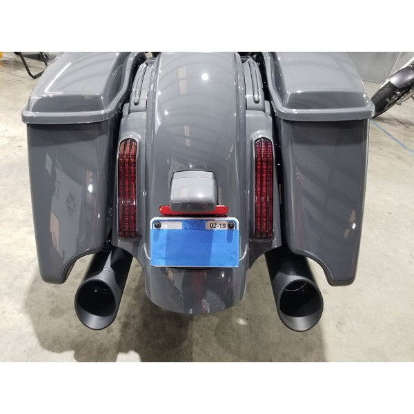 Back view of a motorcycle with storage compartments and exhaust pipes on a concrete floor.