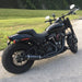 Black motorcycle parked on a paved road with grass and trees in the background