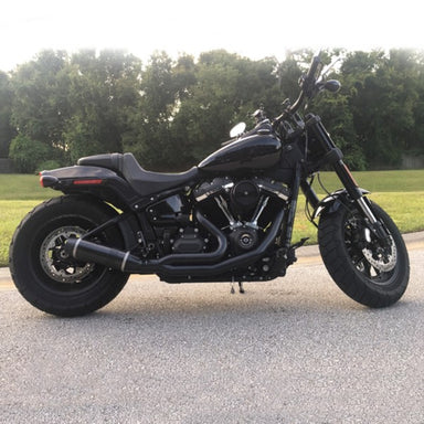 Black motorcycle parked on a road with trees in the background