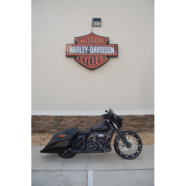 Black motorcycle parked in front of a Harley-Davidson logo on a building.