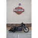 Black motorcycle parked in front of a Harley-Davidson logo on a building.