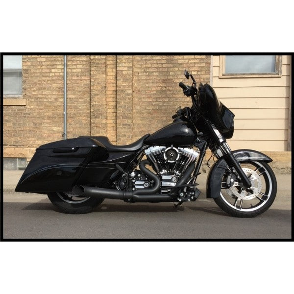 Black motorcycle parked on a street with a brick building in the background